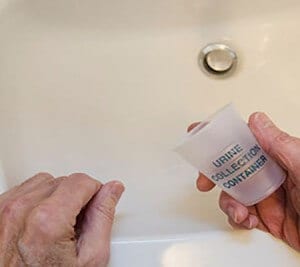 man leaning on sink with urine collection container